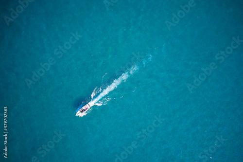 White boat with people aerial view. People in a boat in motion top view. White big boat on turquoise water aerial view.