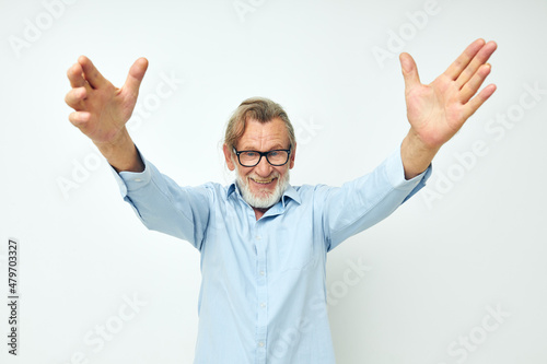 old man in blue shirts gestures with his hands isolated background