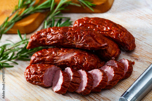 Tasty smoked ham sausages with spices on wooden background. Traditional Czech meat product