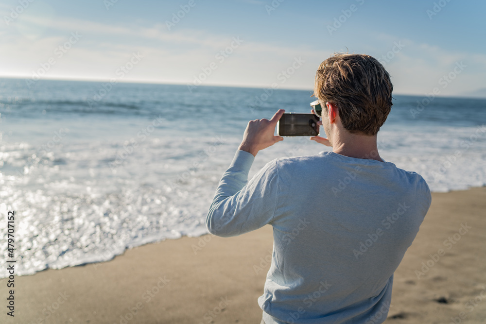 Man using a mobile phone on the beach for taking pictures Man using a mobile phone on the beach for taking pictures
