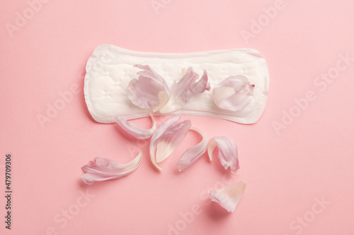 Menstruation pad with flower petals on pink background, woman critical days health care, female gynecological concept, menstruation cycle