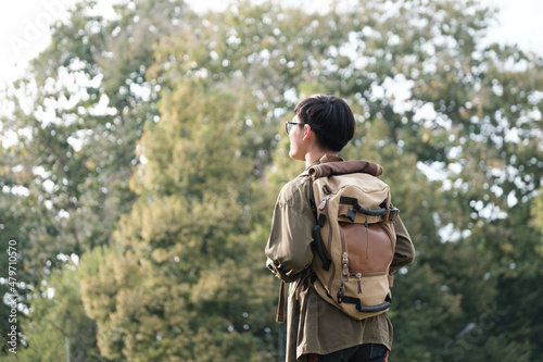 Young man walking with backpacks over natural park background. © ijeab