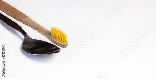 Wooden tooth brush and a spoon diagonally together on white background