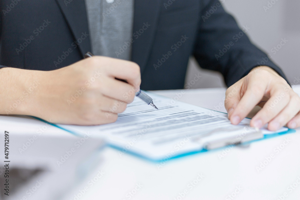 Business partners concept a young businessman holding a pen pointing at profit summary of the recent month showing in document forms Business partners concept a young businessman holding a pen pointing at profit summary of the recent month showing in document forms