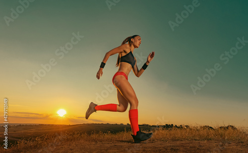 Sprinter run. Strong athletic woman running on black background wearing in the sportswear. Fitness and sport motivation. Runner concept.