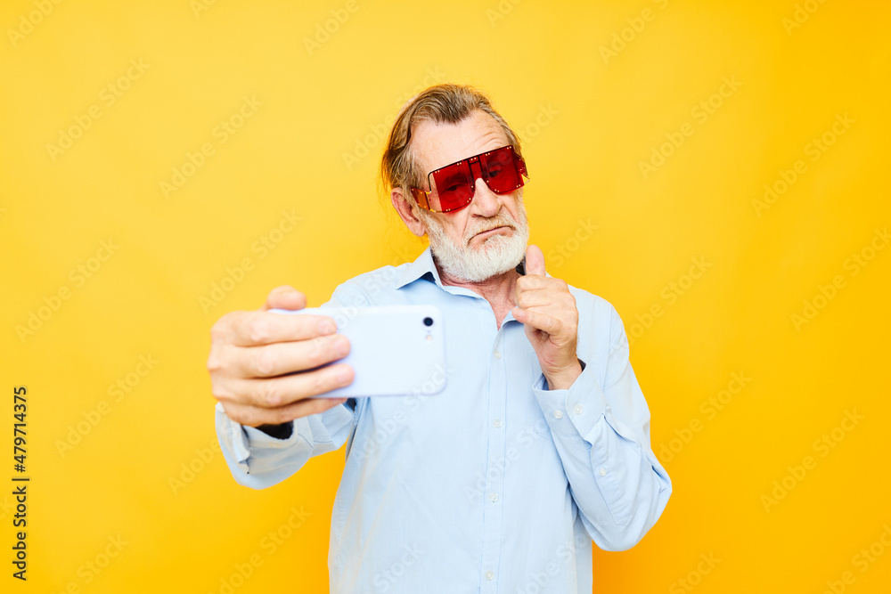elderly man in fashionable red glasses with a phone yellow background elderly man in fashionable red glasses with a phone yellow background