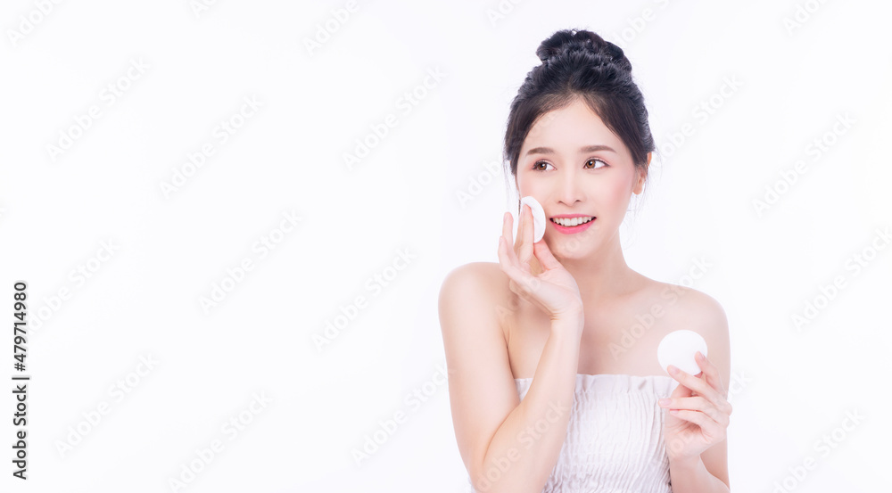 Glamour asian young woman holding white cotton pad removing make-up on white background. Model Asian girl pampering face skin cleaning sponge looking copy space. Healthy skincare and cosmetics concept Glamour asian young woman holding white cotton pad removing make-up on white background. Model Asian girl pampering face skin cleaning sponge looking copy space. Healthy skincare and cosmetics concept