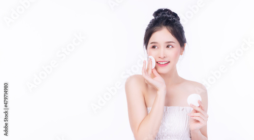 Fotografia Glamour asian young woman holding white cotton pad removing make-up on white background