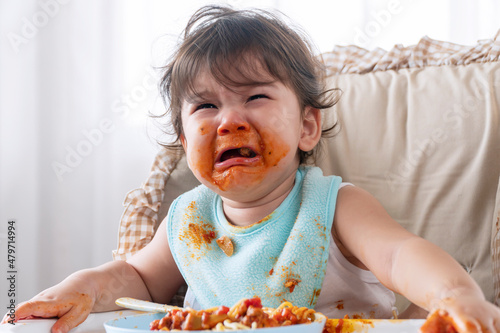 Billede på lærred Unhappy sad toddler child messy tomato sauce on mouth crying