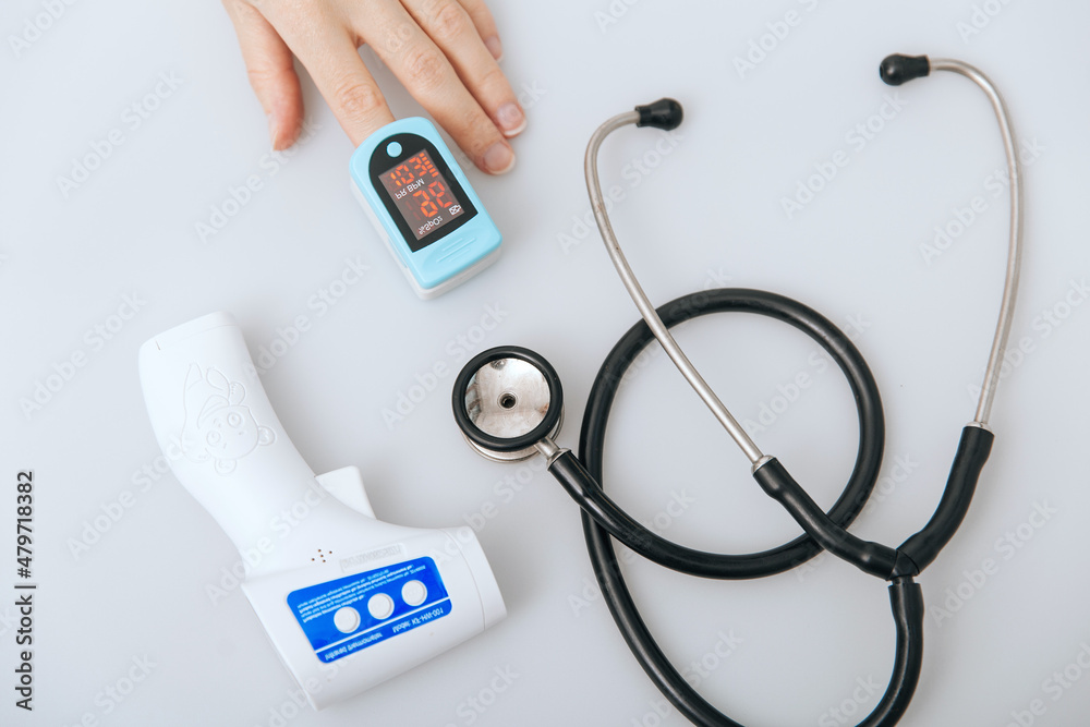 Stethoscope, pulse oximeter and thermometer gun on white background. Phonendoscope. Infrared isometric thermometer gun to check body temperature for virus symptoms. Treatment of cold or flu. Stethoscope, pulse oximeter and thermometer gun on white background. Phonendoscope. Infrared isometric thermometer gun to check body temperature for virus symptoms. Treatment of cold or flu.