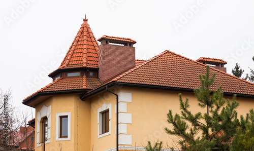 The roof of the house is made of red metal tiles, a beautiful large chimney