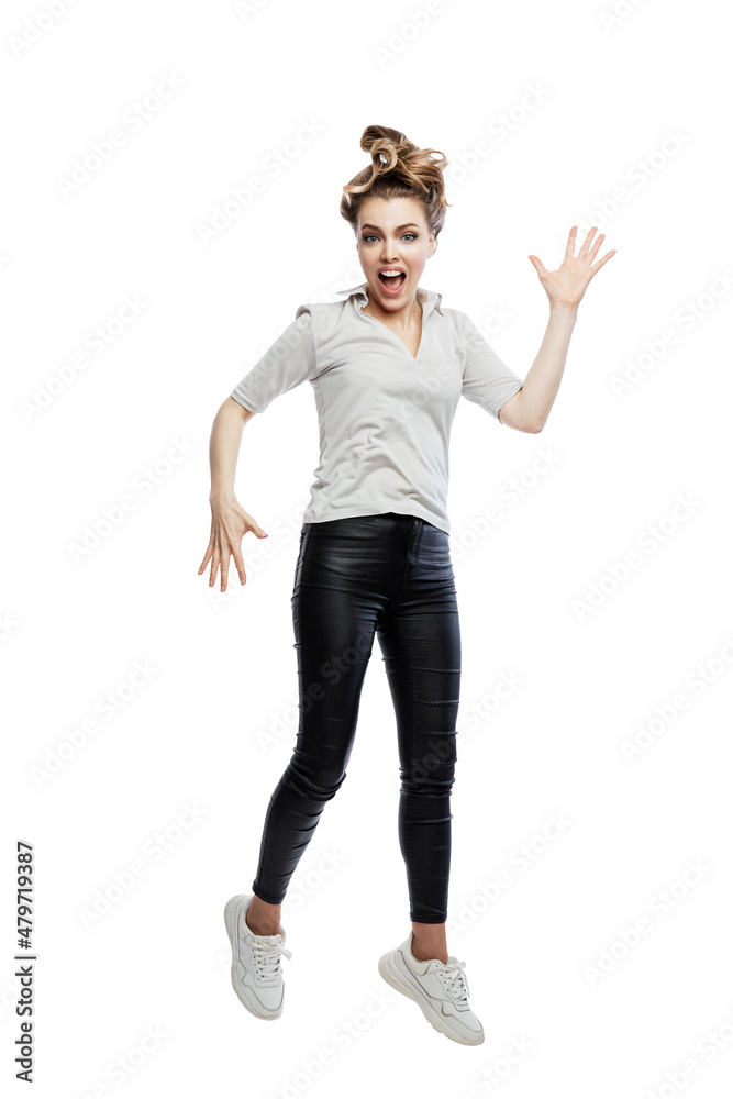 Joyful woman jumping. A beautiful blonde in black leggings, a gray T-shirt and white sneakers. Activity, breathing and positivity. Isolated on white background. Vertical. Joyful woman jumping. A beautiful blonde in black leggings, a gray T-shirt and white sneakers. Activity, breathing and positivity. Isolated on white background. Vertical.