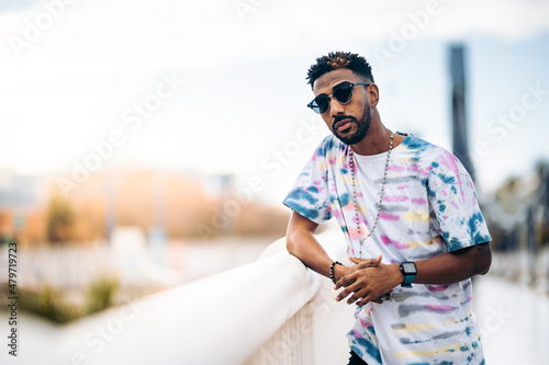 	 Black man in sunglasses leaning on the railing of a bridge  photo