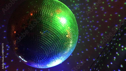 A close up shot of a shiny disco ball slowly spinning and reflecting multi-colored club lights during a dance party inside of a dark, underground nightclub in downtown Atlanta. photo