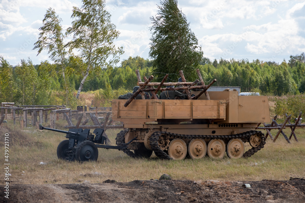 Fototapeta premium Attack of Soviet soldiers. A crawler vehicle carrying a soldier and a machine gun. Reconstruction of the battle of World War II