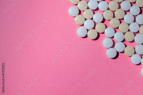 Multicolored round medical tablets on a pink background. Space for text. High quality photo