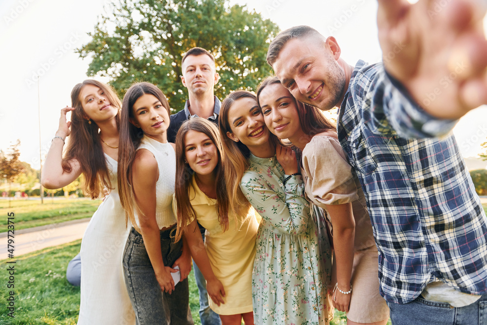 Taking a selfie. Group of young people have a party in the park at summer daytime