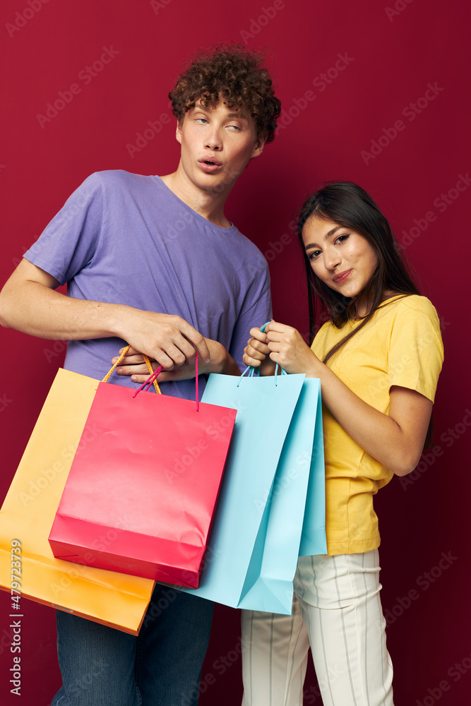cute young couple in colorful T-shirts with bags Shopping isolated background unaltered cute young couple in colorful T-shirts with bags Shopping isolated background unaltered
