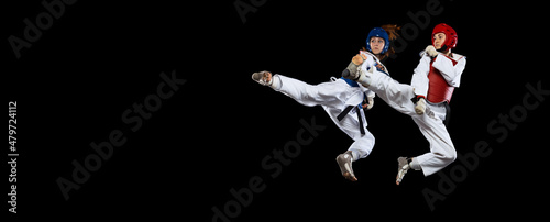 Flyer with two young women, taekwondo athletes training together isolated over dark background. Concept of sport, skills