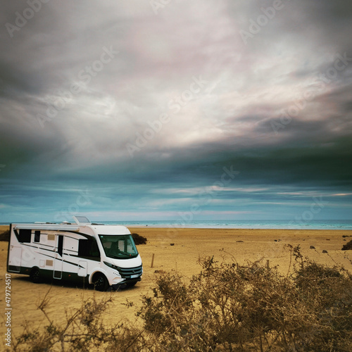 Travel vacation lifestyle with camper parked at the beach with sea view- Recreational vehicle camping car camp in the nature. Holiday concept transport big van free with ocean and sky in background
