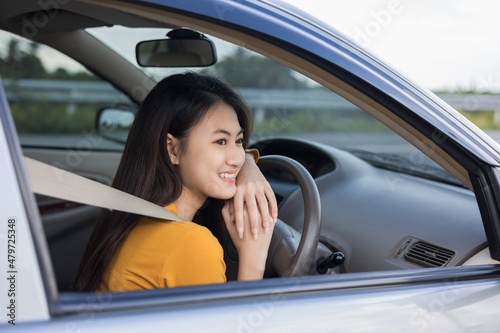 Young beautiful asian women getting new car. she very happy and excited. she sit and touching every detail of car. Smiling female driving vehicle on the road