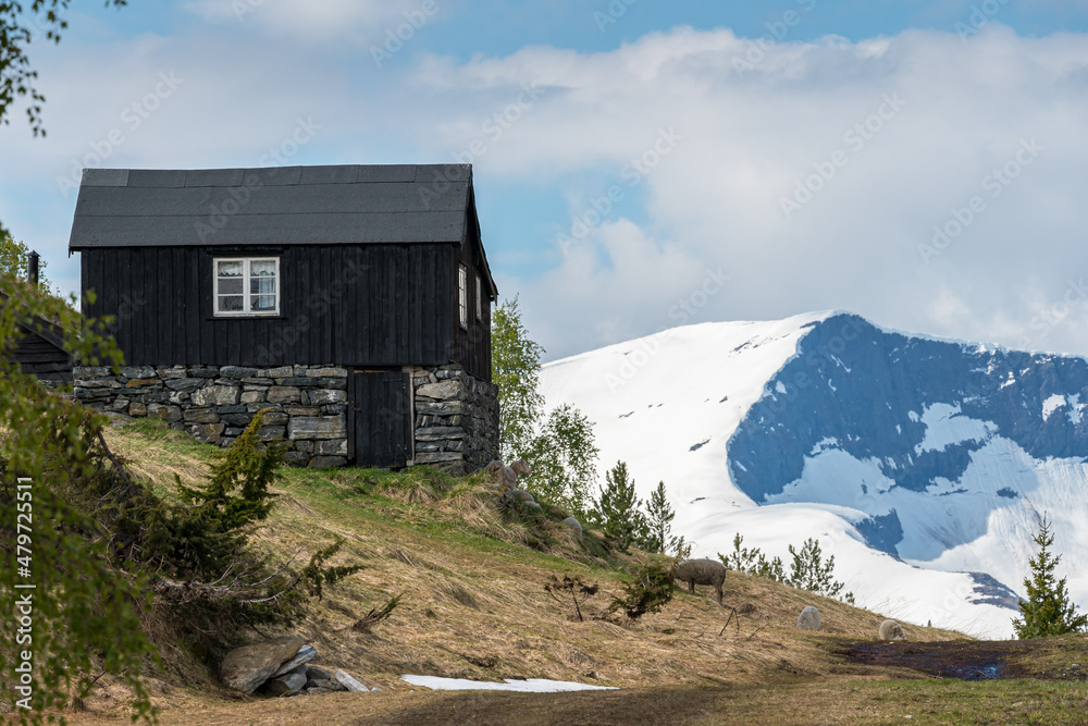 Dark hut with mountains with glacier in background.