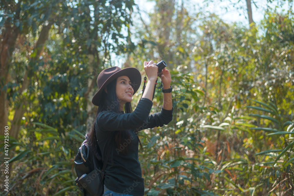 Young woman trekker taking photos of nature with camera in the woods, holidays and traveling concept. Young woman trekker taking photos of nature with camera in the woods, holidays and traveling concept.