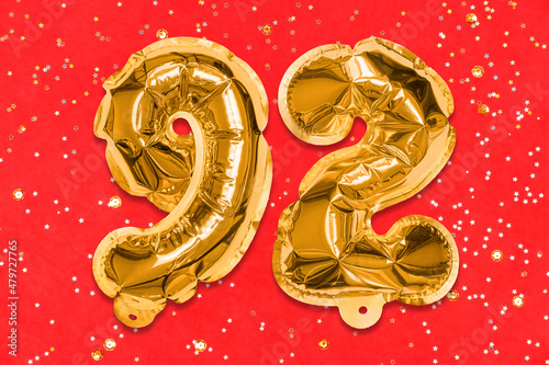 The number of the balloon made of golden foil, the number ninety-two on a red background with sequins. Birthday greeting card with inscription 92. Numerical digit, Celebration event, template. photo