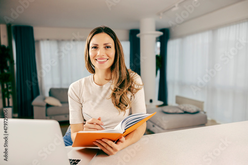 A happy woman following an online lecture from cozy home.