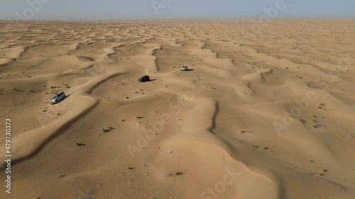 4K: Drone view of the group of 4x4 during the desert safari in the Al Qudra desert of Dubai, United Arab Emirates photo