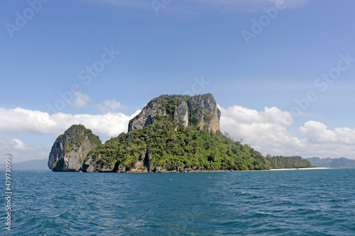 Group of small forested islands in calm blue ocean with blue sky summer background on the horizon. Krabi province, Thailand.