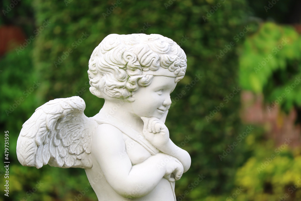 Closeup of an adorable smiling cupid sculpture in the garden
