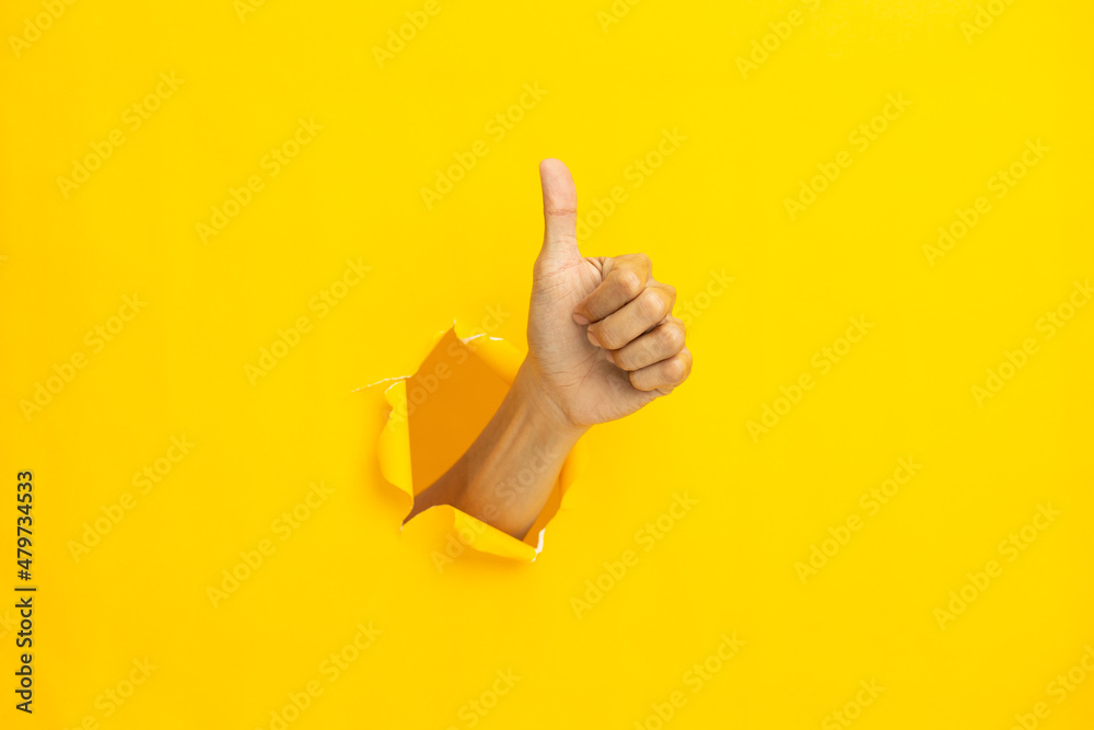 © suriya - Close-up of male hand showing thumbs up on yellow background. © suriya - Close-up of male hand showing thumbs up on yellow background.