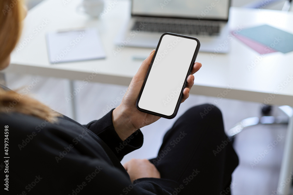 A female using a smartphone at her office desk. A female using a smartphone at her office desk.