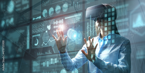 Businesswoman in vr glasses touching graphs on a virtual screen with HUD interface. Internet of things and futuristic technologies concept. Mixed media..