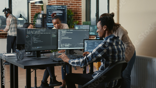 Obraz w ramie Software developer looking at running code on multiple screens takes off glasses and doing high five hand gesture with colleague programer. Programmers celebrating successful online cloud computing.