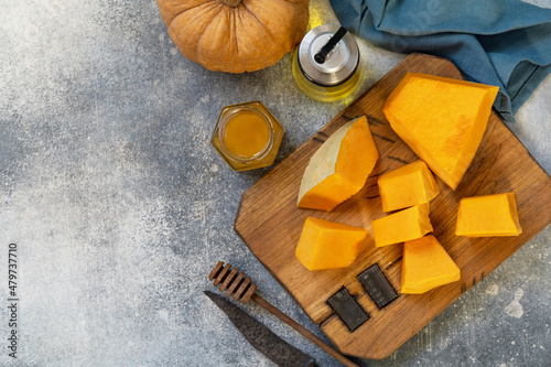Raw pumpkin and honey for prepare baking over gray stone background. Top view flat lay. Copy space.