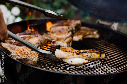 Close-up of grilling steaks of meat on barbecue with open flames. Backyard BBQ