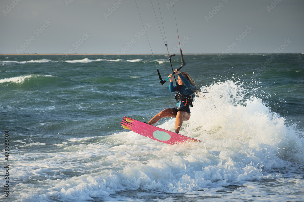 Professional kitesurfer caucasian woman rides big waves in windy weather. Kitesurfing