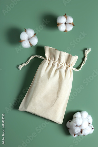 Cotton reusable bag and cotton buds on green background. Minimalism shopping.