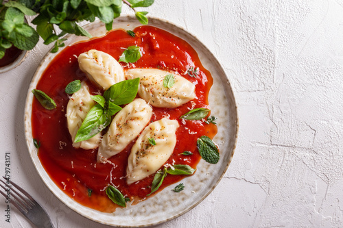 traditional Italian food culurgiones with tomato sauce and basil photo