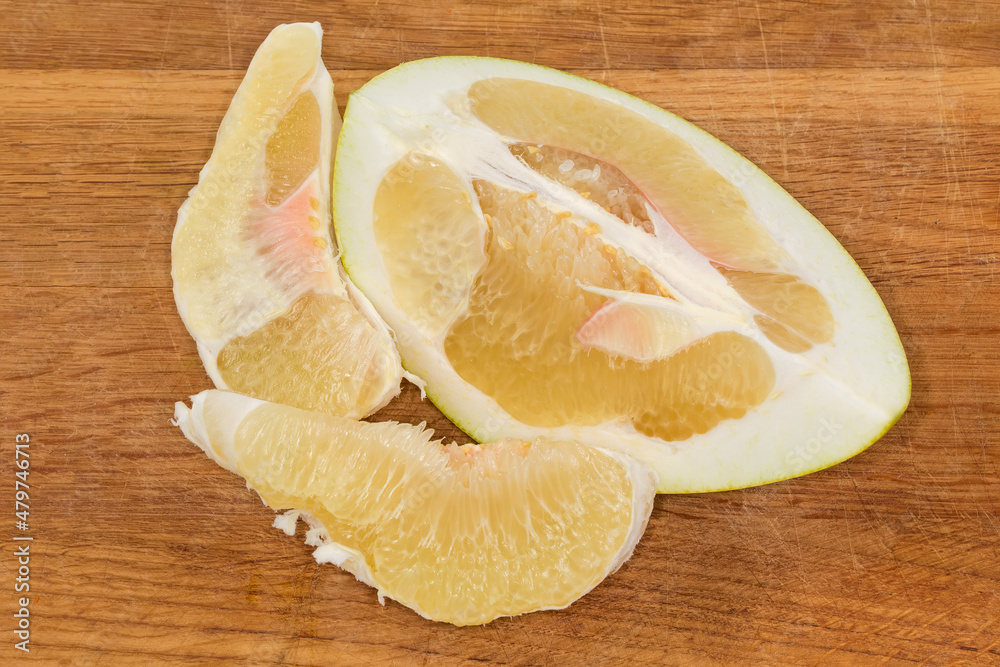 Slices of ripe pomelo on a wooden cutting board Slices of ripe pomelo on a wooden cutting board