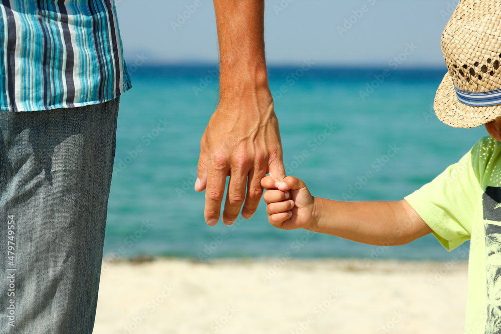 The parent holds the child's hand on the beach The parent holds the child's hand on the beach
