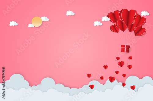 Paper art of Valentine's day festival with heart-shaped paper and cloud shape paper and sun-shaped paper on the pink sky.