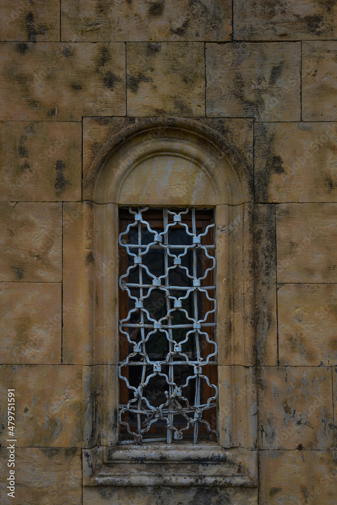 Background of stone castle wall. Old brown wall with window. Wall texture. Rock blocks in old medieval wall. Graphic texture element.