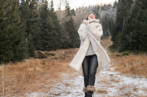 Happy female traveler resting in winter forest on sunny day. Camel brown. Rusty red color. Nature grasses, plants, trees and parks. Fresh air, rocky mountains