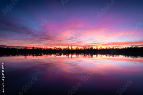Beautiful sunset landscape sunset on the lake, reflected on the calm water - France © Yannick
