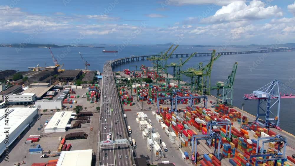 Aerial view of traffic on the Rio-Niteroi bridge next to large container port and shipping docks in Rio de Janeiro, Brazil. 