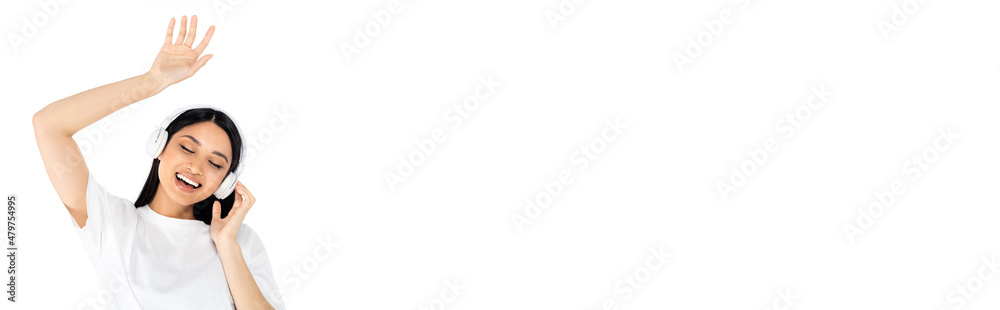 happy asian woman in headphones dancing with closed eyes isolated on white, banner. happy asian woman in headphones dancing with closed eyes isolated on white, banner.