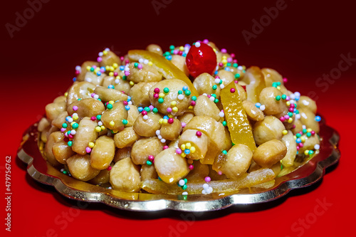 Struffoli, typical Neapolitan pastry consisting of many small balls of dough fried in oil and wrapped in warm honey. Decorated with colored sprinkles. photo